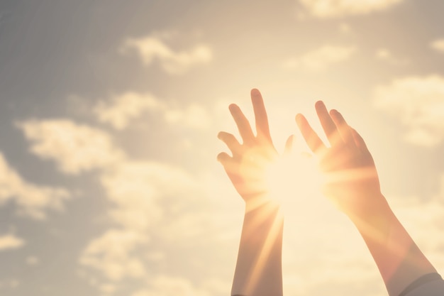 Vrouw handen reikt naar de lucht en de zon