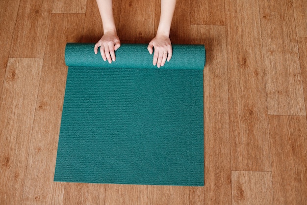 Foto vrouw handen rollen een yoga mat