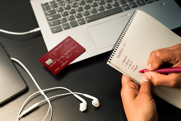 Vrouw handen schrijven boodschappenlijstje op de notebook klaar voor online winkelen