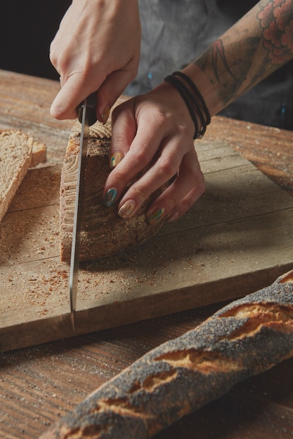 Vrouw handen snijden vers brood op een houten bord