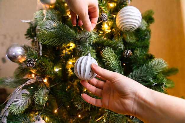 Vrouw handen versieren kerstboom kerstboom met wit en zilveren versieringen ornamenten speelgoed ...