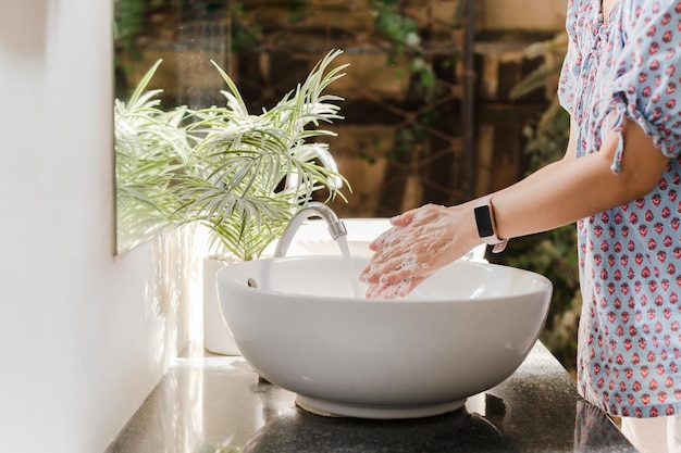 Vrouw handen wassen met kraanwater onder kraan bij witte gootsteen