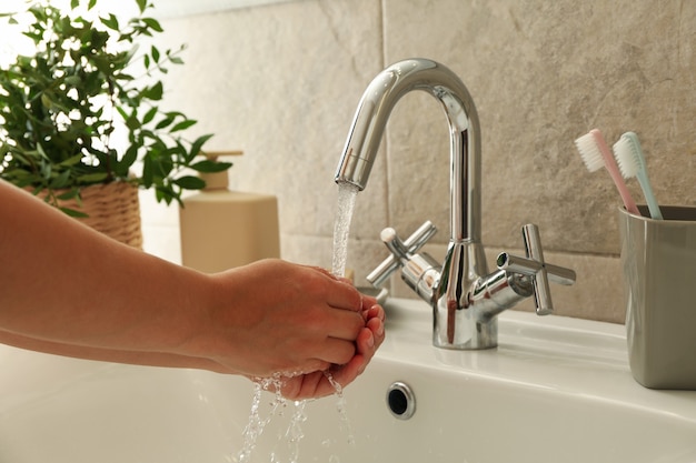 Vrouw handen wassen onder de waterkraan in de gootsteen