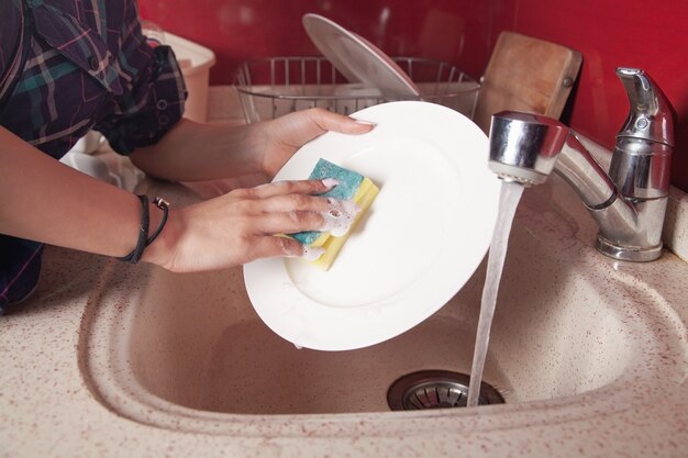 Vrouw handen wassen van witte plaat in aanrecht