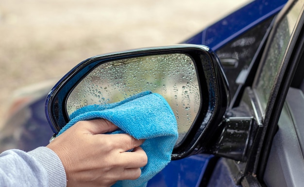 vrouw handreiniging intrekbare achteruitkijkspiegel zijwaartse autospiegel met microvezeldoek droog afvegen. herfst