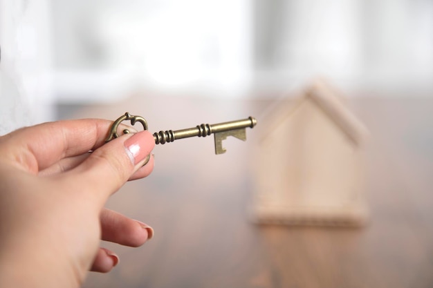 Vrouw handsleutel met huis op tafel