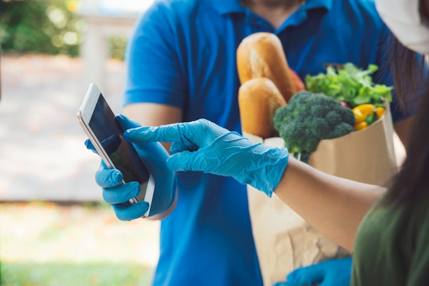 Vrouw handtekening in digitale mobiele telefoon toe te voegen na kruidenierswinkel die voedsel levert aan een vrouw