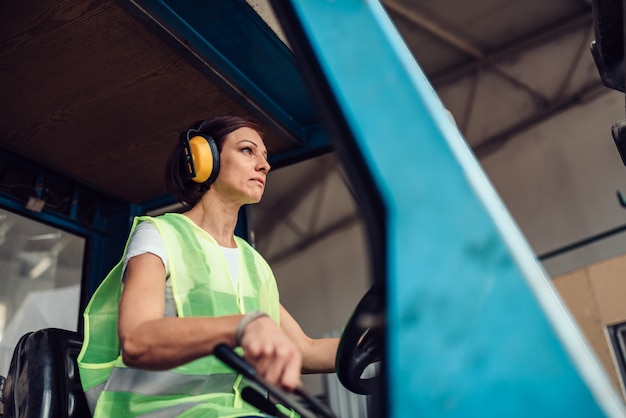 Vrouw heftruck operator rijden voertuig