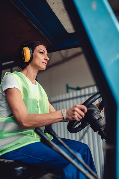 Vrouw heftruck operator rijden voertuig