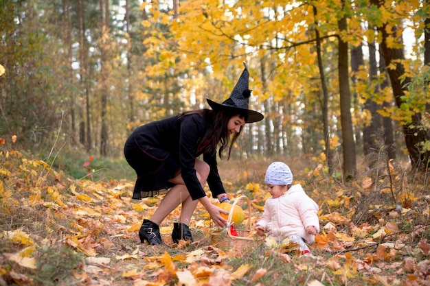 Vrouw heks speelt met een klein kind in de herfst bos halloween concept kostuums heks en konijn