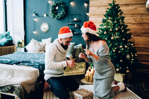 Vrouw helpt man kerstcadeau te openen