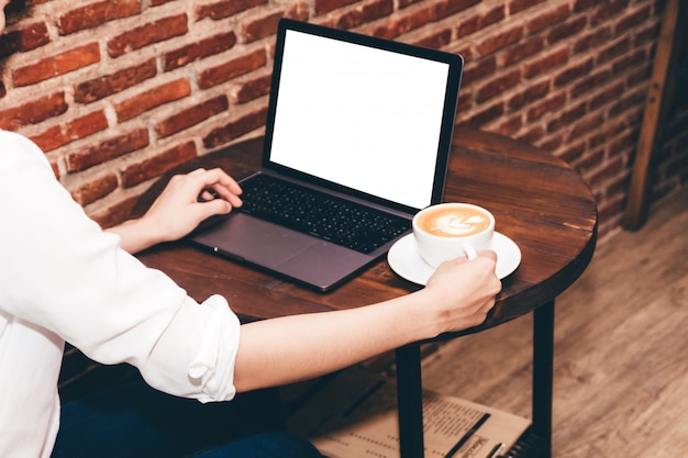 Vrouw het drinken koffie en het werk aan laptop computer bij koffiewinkel