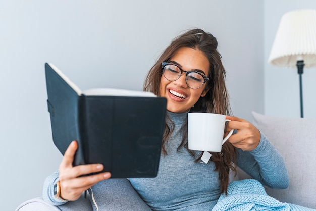 Vrouw het drinken thee en het lezen van boek op de bank