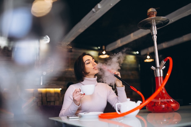 Vrouw het drinken van thee en het roken van shisha