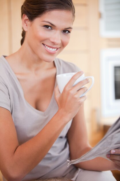 Vrouw het drinken van thee tijdens het lezen van de krant