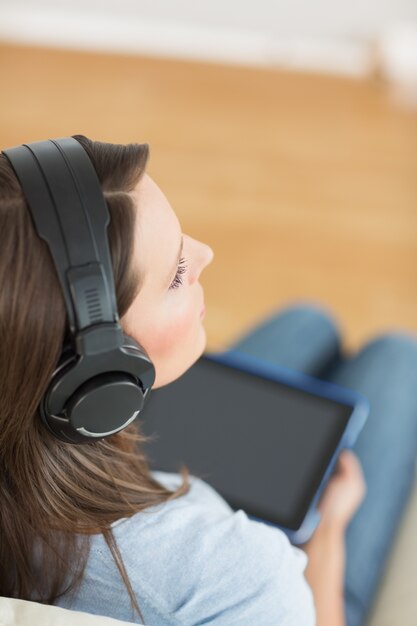 Vrouw het luisteren muziek met haar digitale tablet op bank