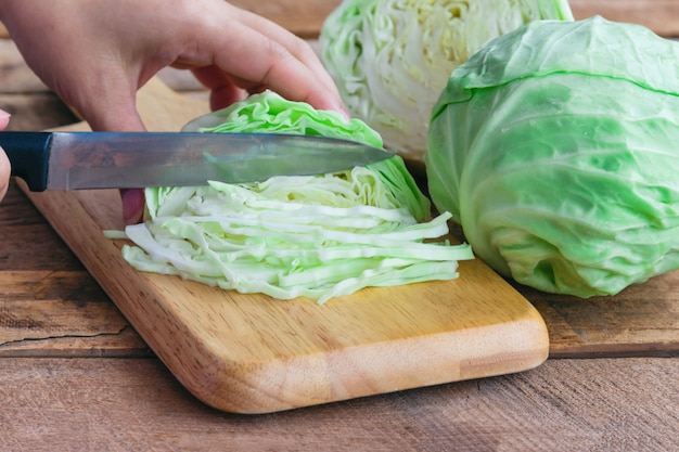 Vrouw het mes keuken snijden verse kool voor te bereiden voor het koken op hout snijplank.