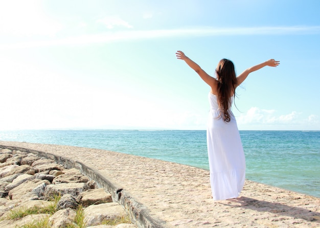 Vrouw het ontspannen bij het strand met open wapens genietend van haar vrijheid