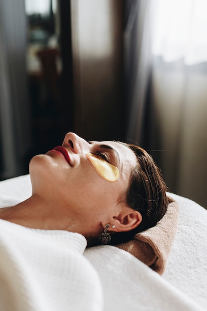 Vrouw het ontspannen met een gouden behandeling van het oogmasker