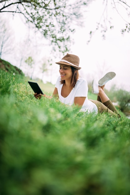 Vrouw het ontspannen op groen gras en het gebruiken van tablet.