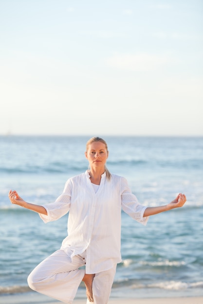 Vrouw het praktizeren yoga bij het strand