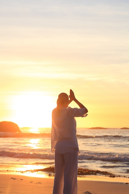 Vrouw het praktizeren yoga tijdens de zonsondergang bij het strand