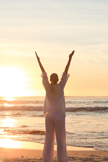 Vrouw het praktizeren yoga tijdens de zonsondergang