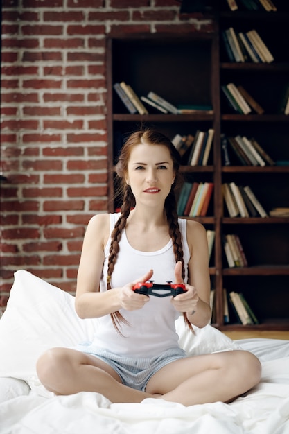 Vrouw het spelen op console op het bed thuis