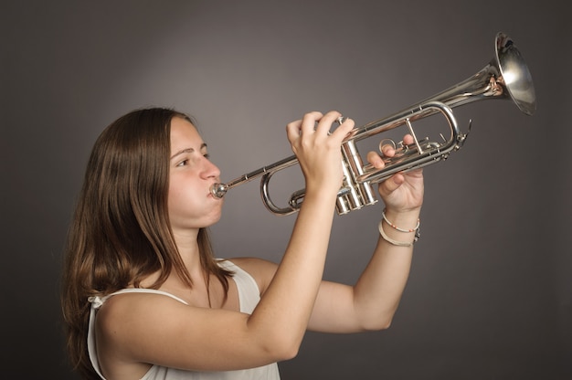 Vrouw het spelen trompet op grijs