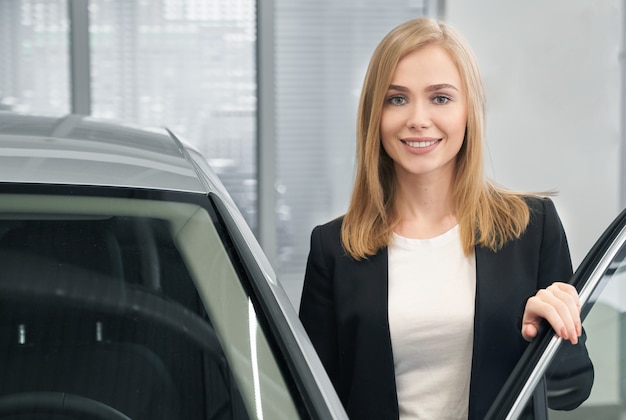 Vrouw het stellen dichtbij auto in autodealer.