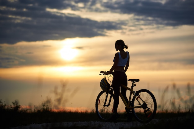 Vrouw het stellen dichtbij fiets en enoying aard.