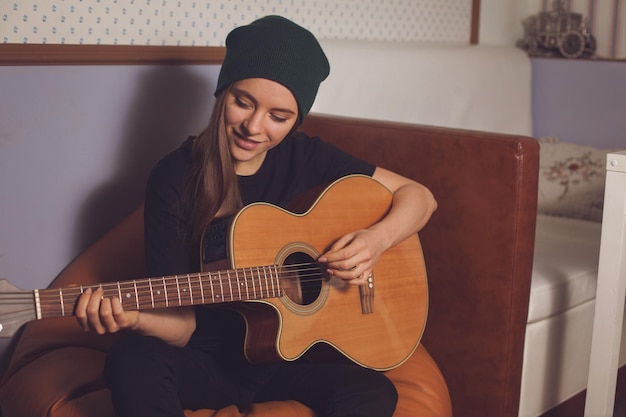 Vrouw hipster spelen op gitaar en genieten van muziek