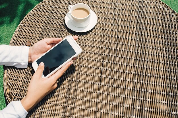 Vrouw houden en met behulp van slimme telefoon met zwart leeg leeg scherm bij cafetaria