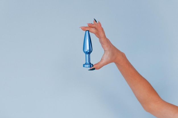 Vrouw houdt blauw seksspeeltje in handen in de studio. Conveptie van intimiteit.