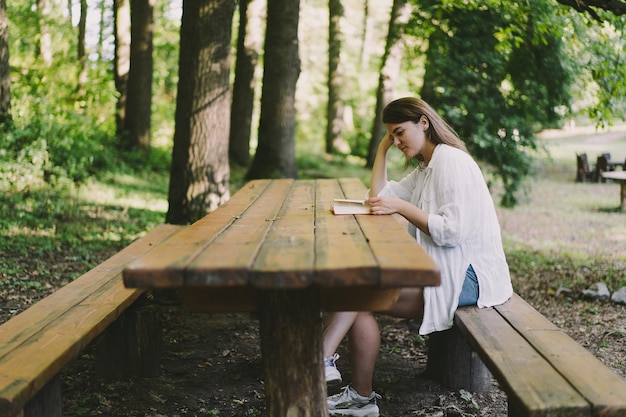 Vrouw houdt boek in haar handen lezen van het boek zittend op een bankje in de buitenlucht