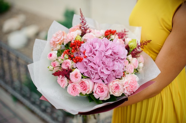 Vrouw houdt boeket rozen, astilba, anjers en hortensia