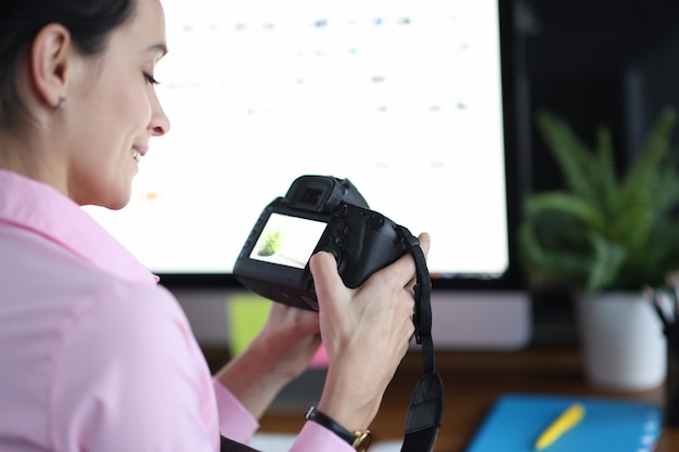 Vrouw houdt camera vast en drukt op knoppen op het concept van de fotograaf van het beroep op de werkplek