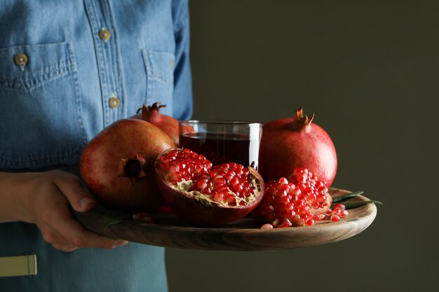 Vrouw houdt dienblad met granaatappelsap en ingrediënten, close-up