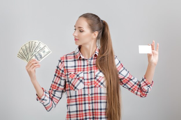 Vrouw houdt dollarbiljetten en plastic kaart vast