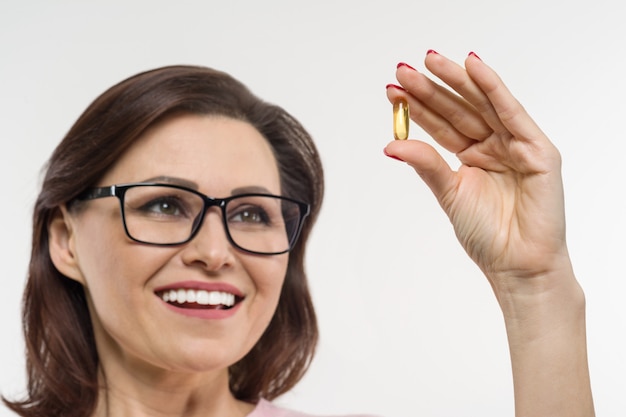 Vrouw houdt een capsule met vitamine E, visolie