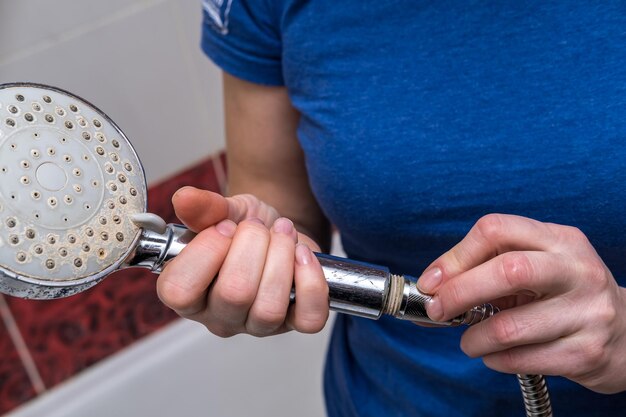 Vrouw houdt een kapotte douchesproeier in haar handen en verandert in een nieuwe