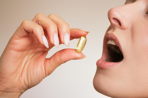 vrouw houdt een pil met haar vingers vast en stopt het in haar mond en neemt medicijnen en vitamines close-up