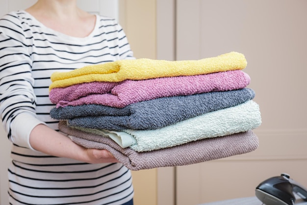 Vrouw houdt een stapel schone handdoeken vast Opvouwbaar schoon linnen huis schoonmaken en voor huishoudtextiel zorgen