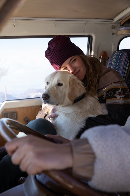 Foto vrouw houdt haar labrador vast tijdens een winterreis in haar camper