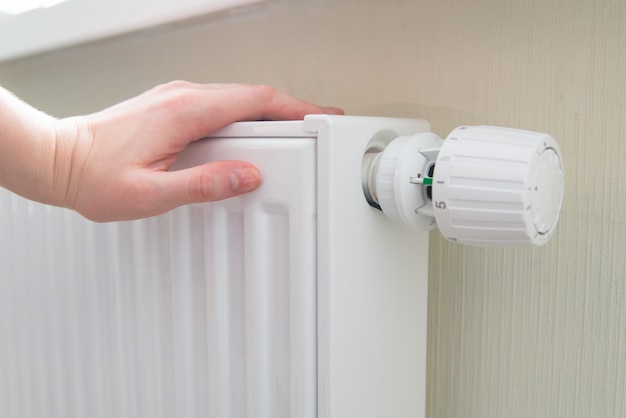 Vrouw houdt hand op de radiator