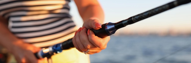 Vrouw houdt hengel met haspel vast tijdens het vissen in de zee vissersvrouw die staat met spinnen