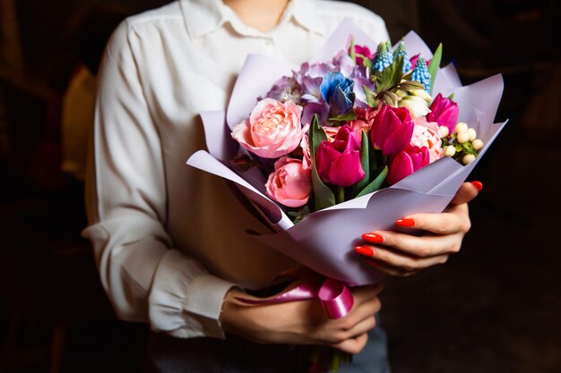 vrouw houdt in haar hand een prachtig boeket met veelkleurige verse bloemen. Een geweldig cadeau voor elke gelegenheid.