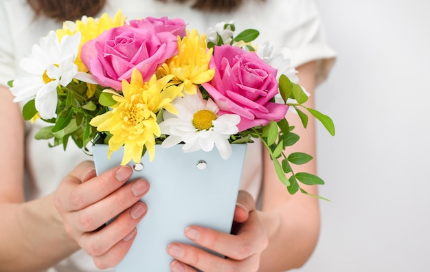 Foto vrouw houdt in haar handen een bloemenarrangement van rozen madeliefjes en chrysanthemums