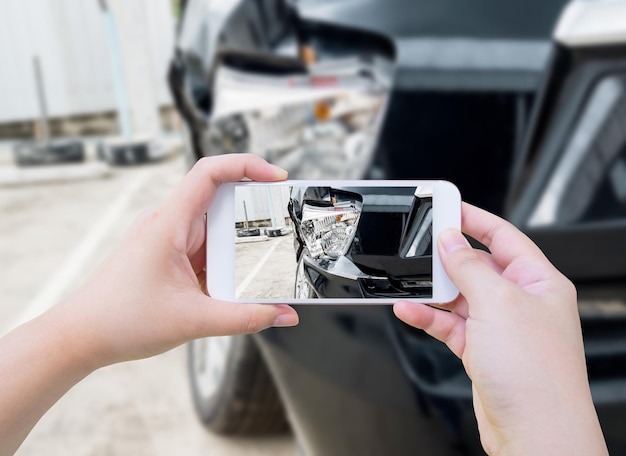 Foto vrouw houdt mobiele smartphone vast die auto-ongeluk fotografeert voor verzekering