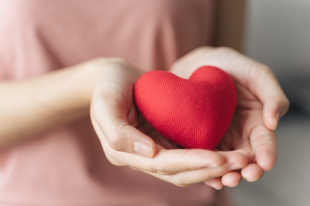 Vrouw houdt rood hart liefde ziektekostenverzekering donatie gelukkige liefdadigheid vrijwilliger geestelijke gezondheid dag